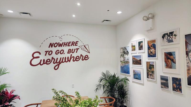 The interior of Fora Travel's New York pop-up, with travel photographs and a red slogan on a white wall