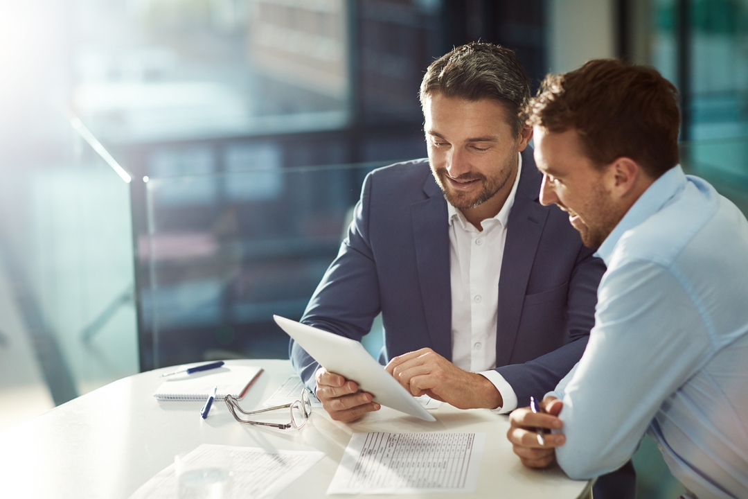 Two business analysts reviewing research together on a tablet