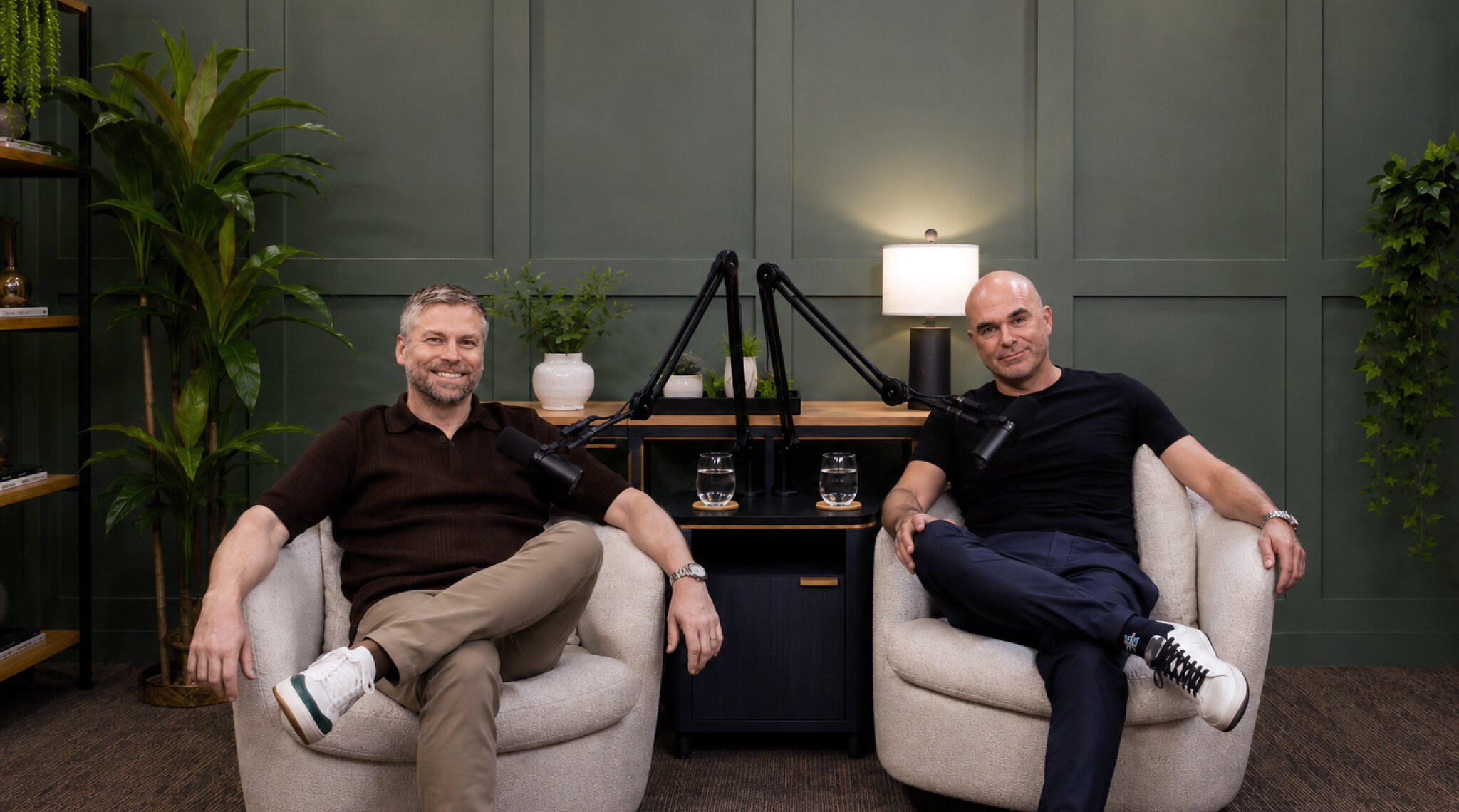 Mike Savage and Gary Milkwick seated beside microphones in a plant-filled podcast studio
