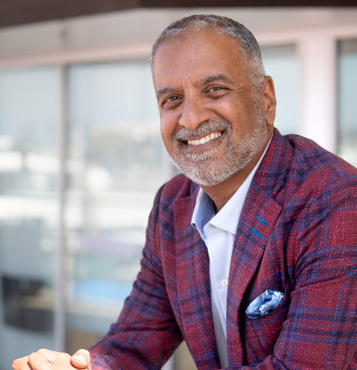 Portrait of 1105 Media CEO Rajeev Kapur wearing a patterned burgundy jacket