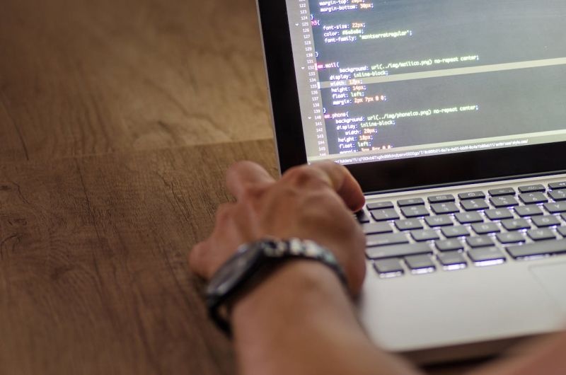 A hand at a laptop displaying website code, in an illustrative photograph shared by 2Logix