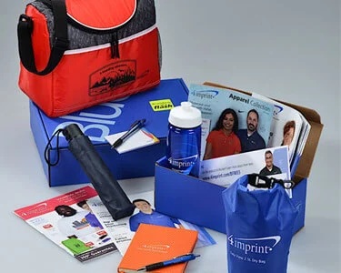 A 4imprint Blue Box surrounded by sample bags, a bottle, an umbrella and printed materials