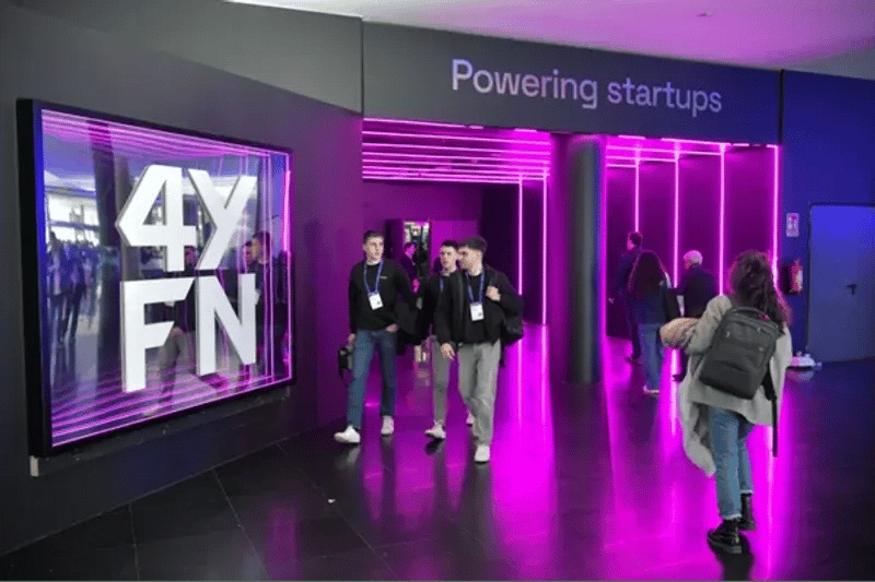 Visitors walk past illuminated 4YFN signage at the event