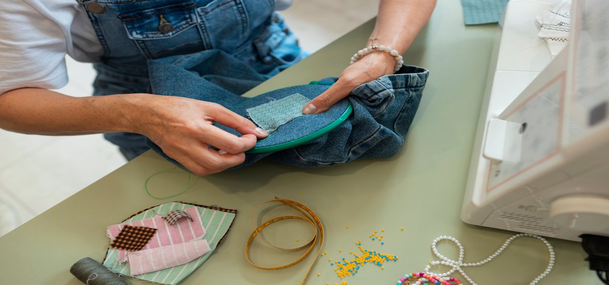 Hands guiding fabric through an embroidery hoop