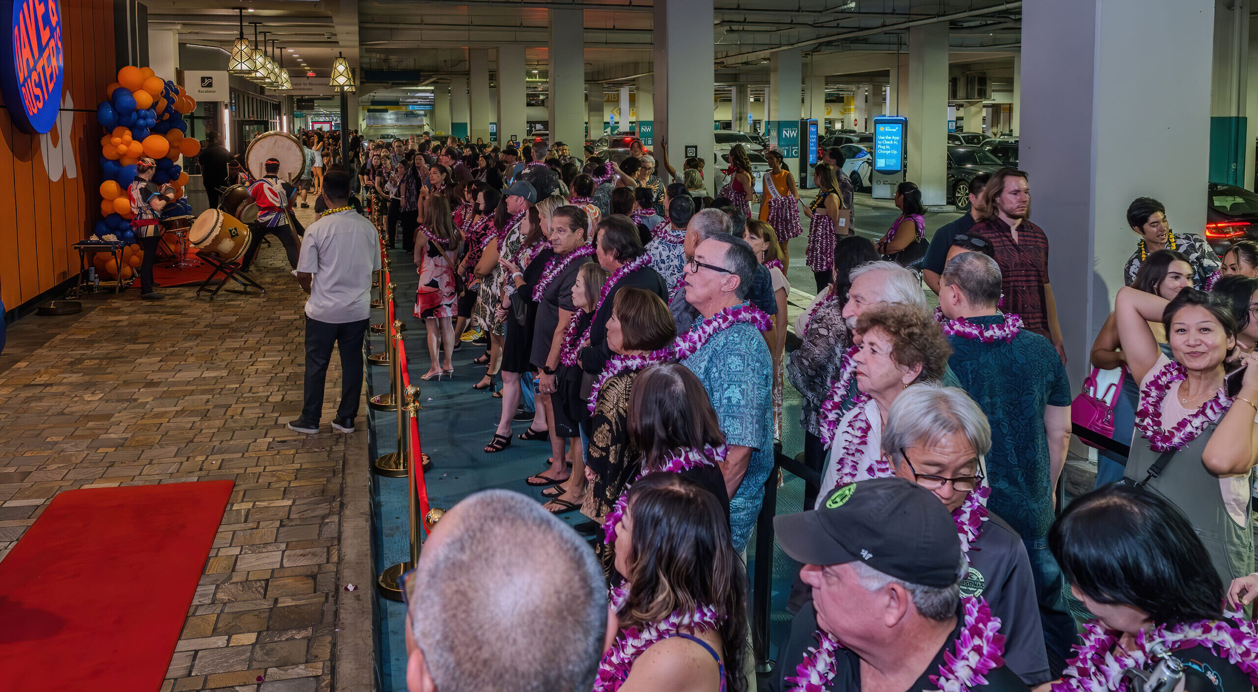 A crowd wearing flower lei gathers outside Dave and Buster’s Ala Moana during a launch event
