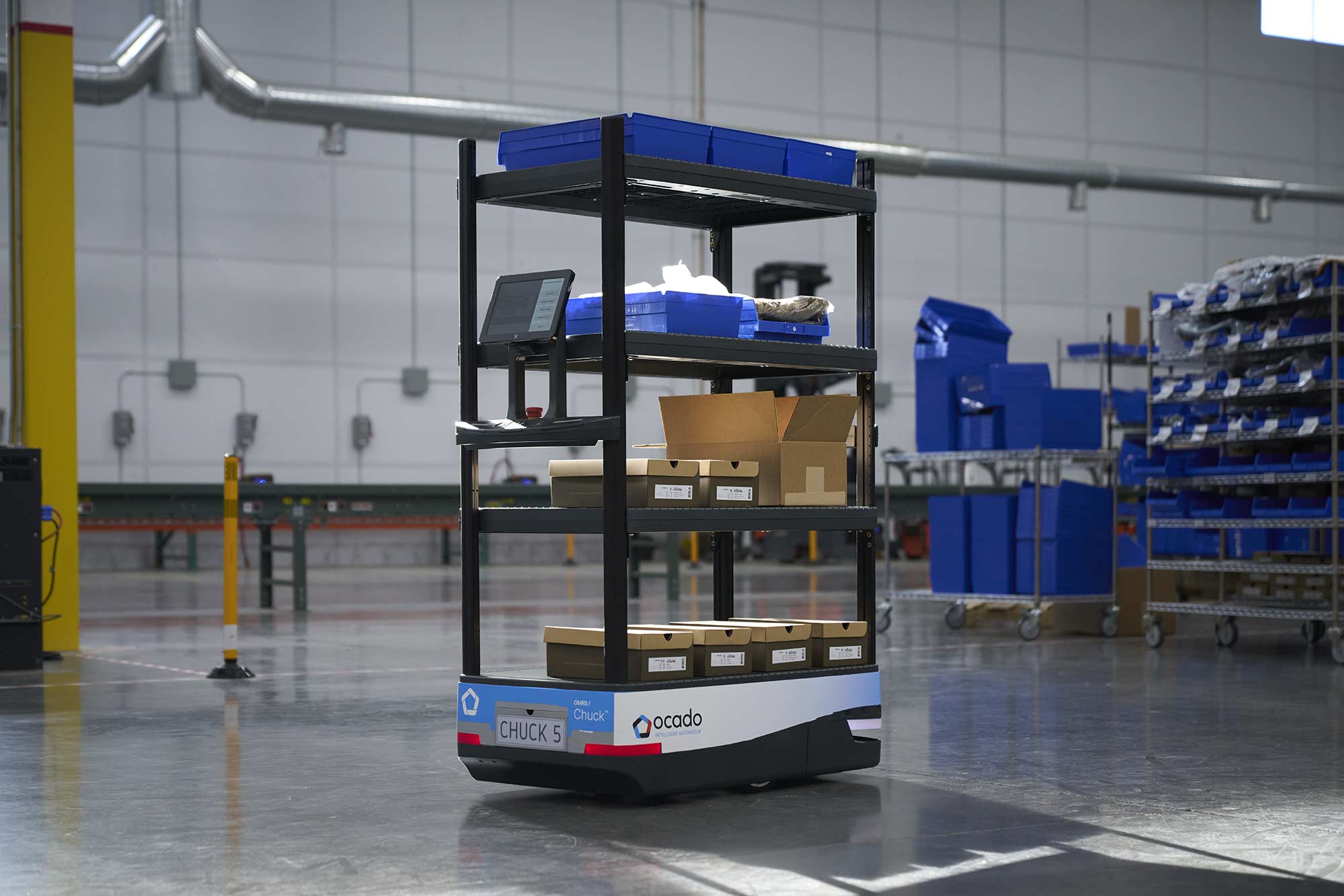 Chuck mobile warehouse robot carrying blue totes and cardboard cartons