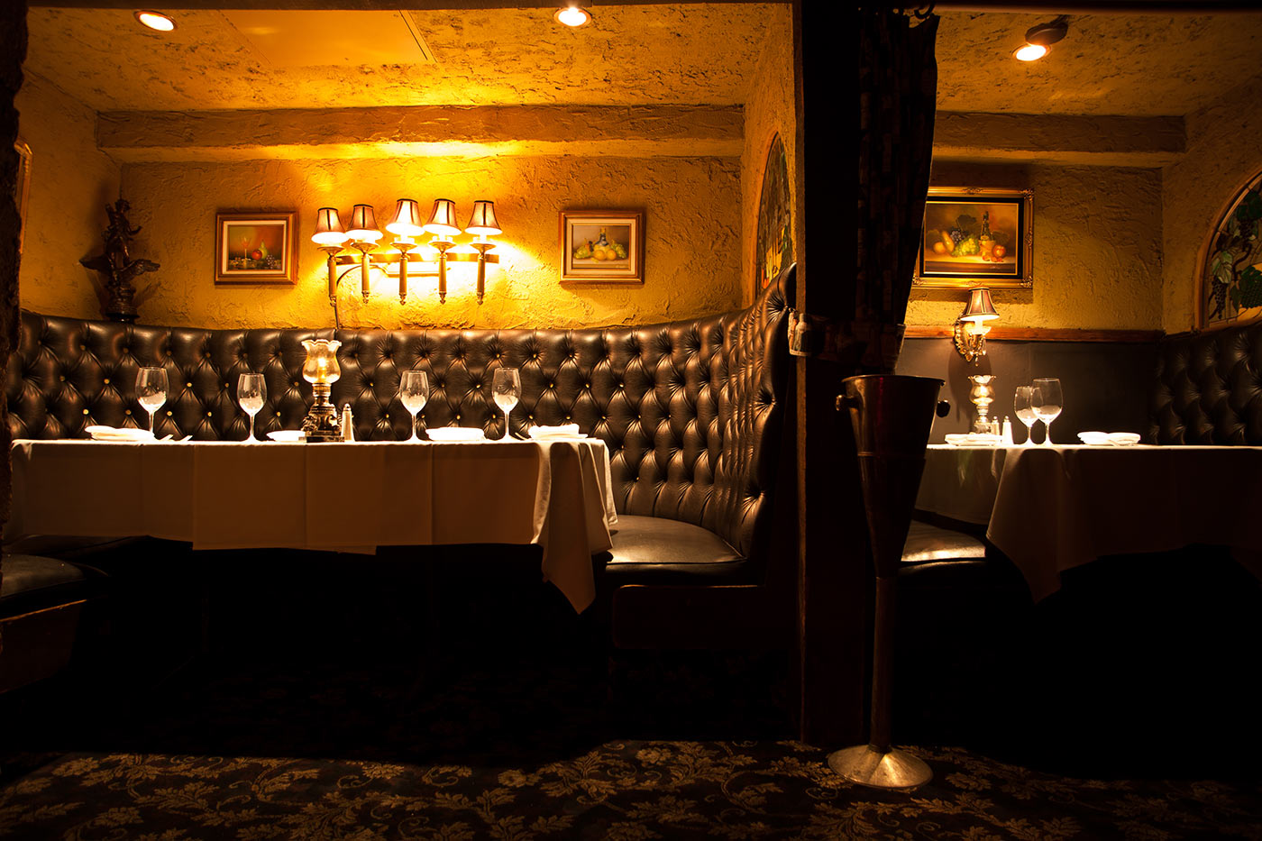 An intimate restaurant dining room with amber lighting and white tablecloths