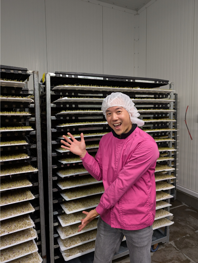 Vegbed founder Albert Lin in protective clothing beside germination racks during an 80 Acres Farms visit