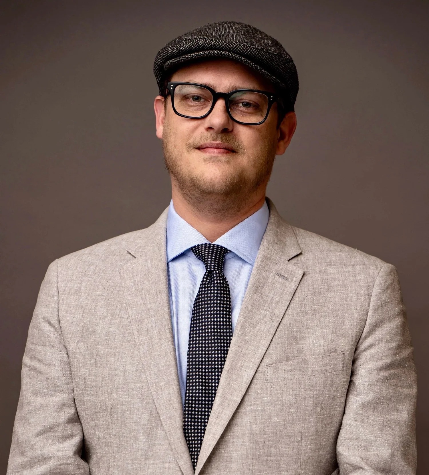 818 Political digital specialist Ben Allen in glasses, a cap and a light suit