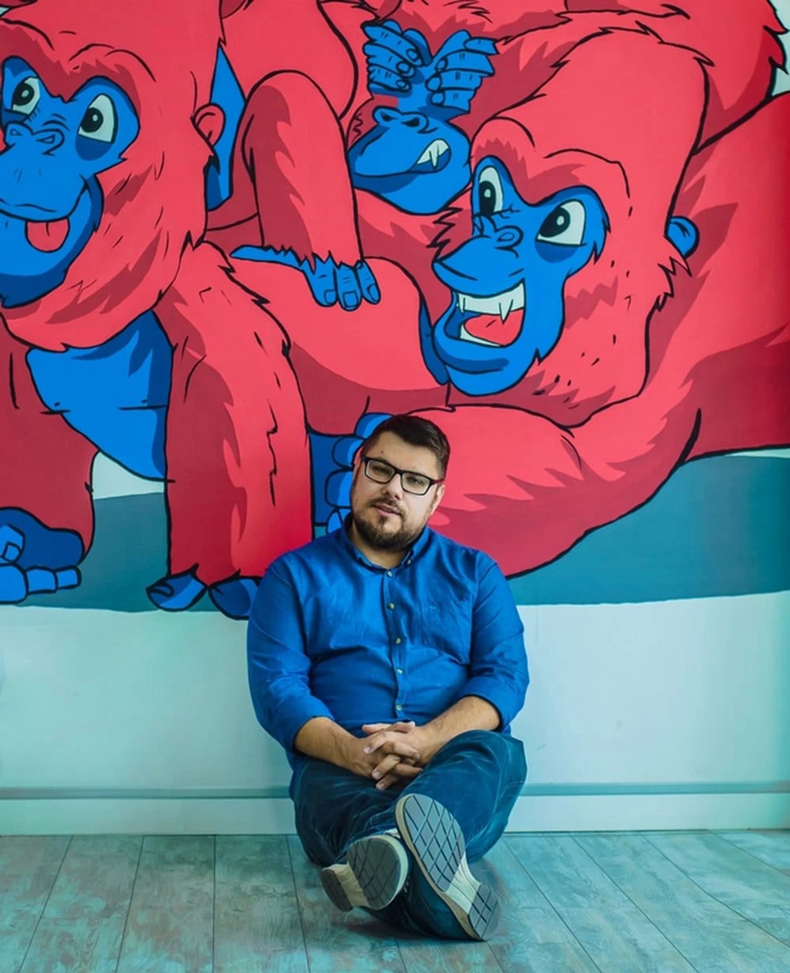 Aleksey Ivankin seated in front of the Opendatabot office mural