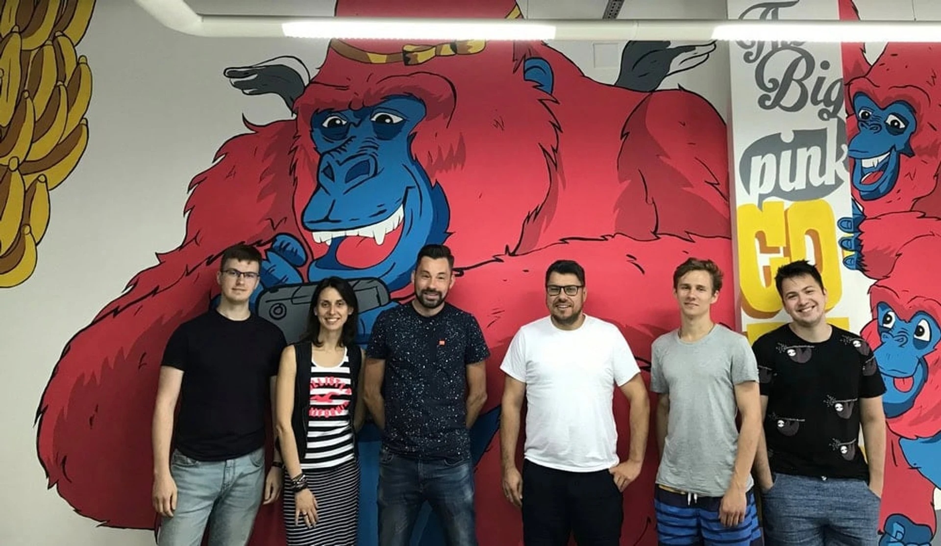 Six Opendatabot team members standing in front of a bright pink and blue gorilla mural