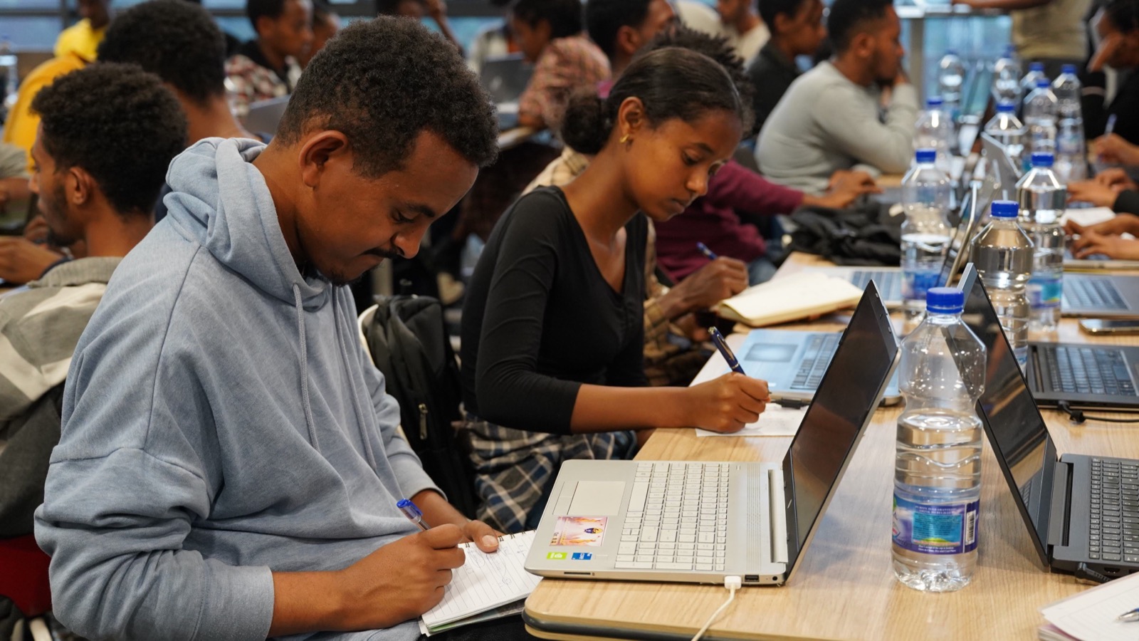 A2SV students taking notes beside their laptops during an in-person training session