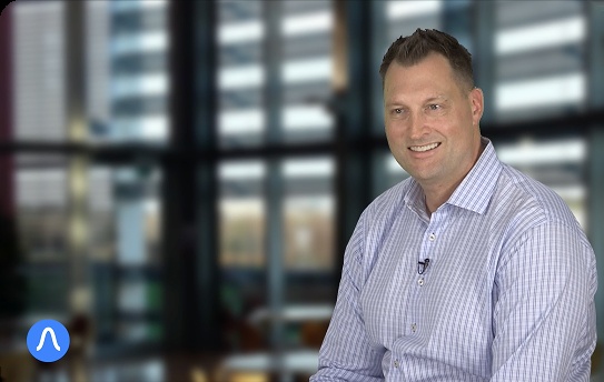 Aaron Brodt wearing a striped shirt and lapel microphone during an Amplify interview