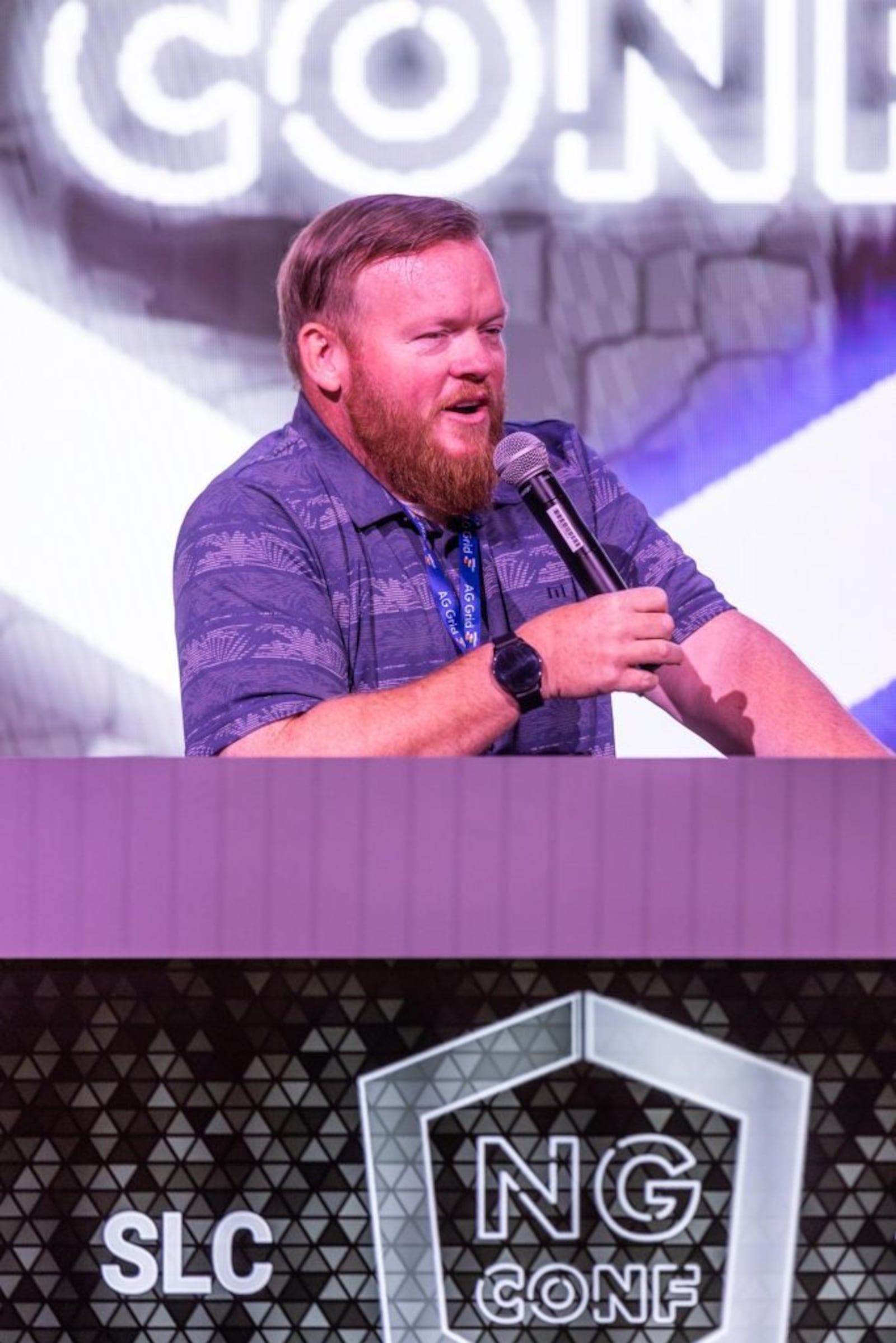 Aaron Frost holding a microphone on stage at ng-conf