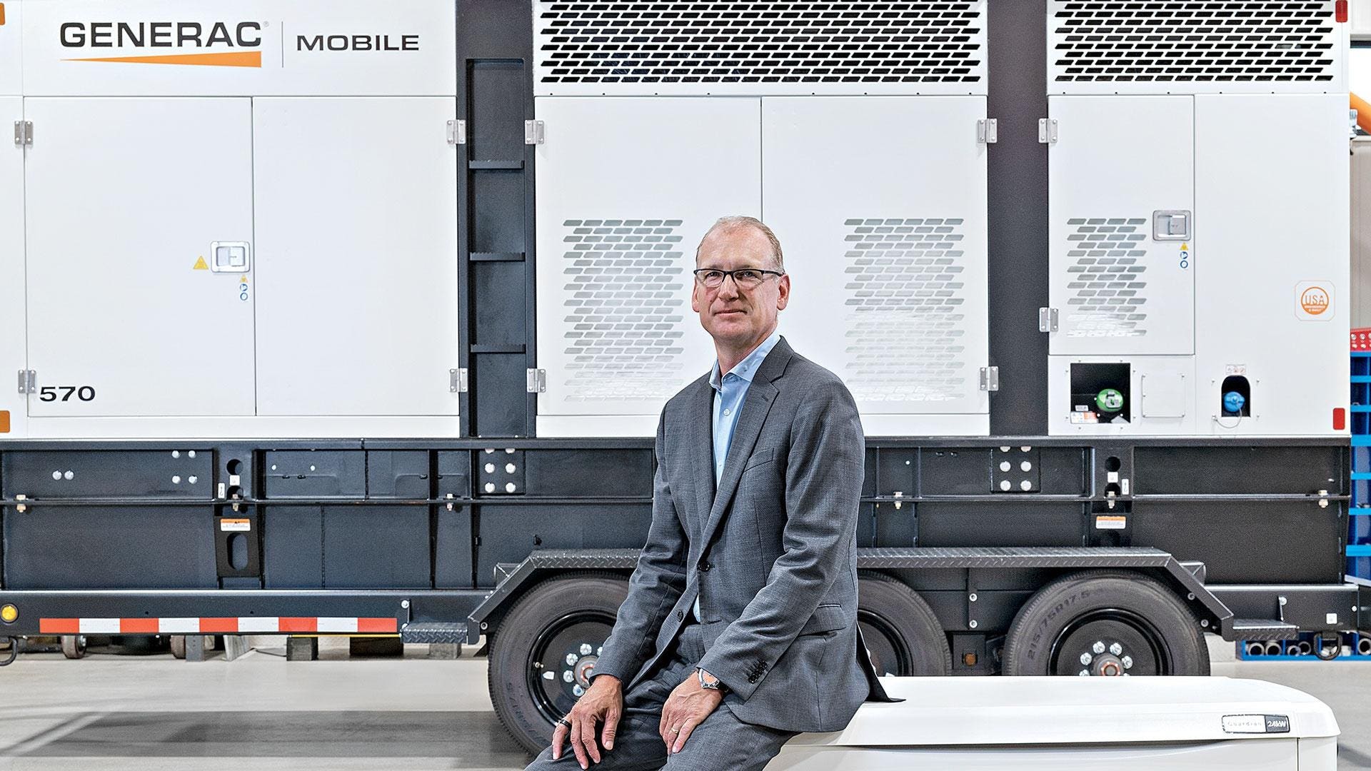 Aaron Jagdfeld seated in front of a large Generac Mobile generator at the Whitewater plant