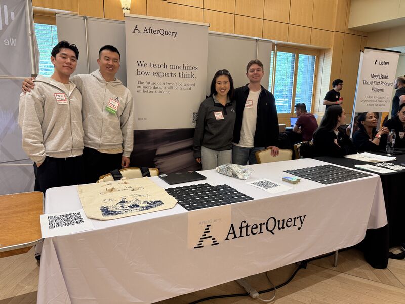 Four AfterQuery team members standing behind a recruiting table at Stanford's career fair