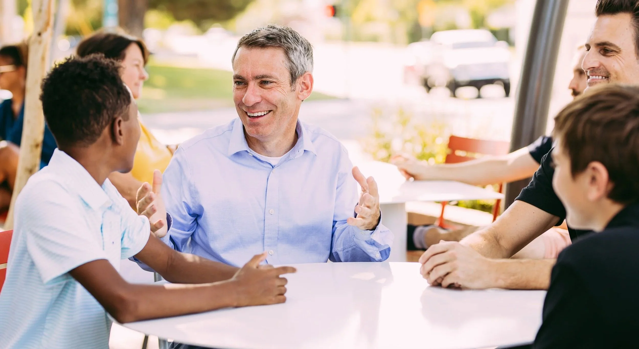 Aaron Lieberman smiling and talking with a group around an outdoor table.