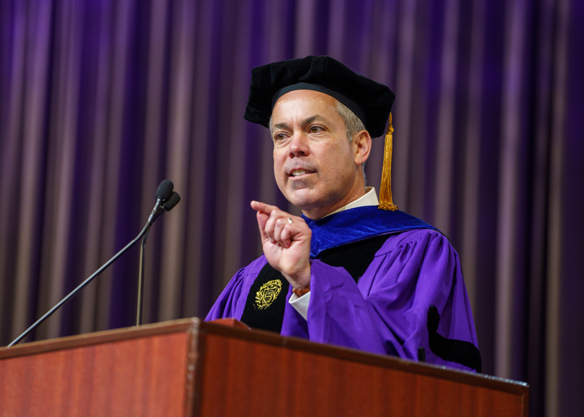 Aaron Saak in academic regalia speaking at a Northwestern Engineering lectern