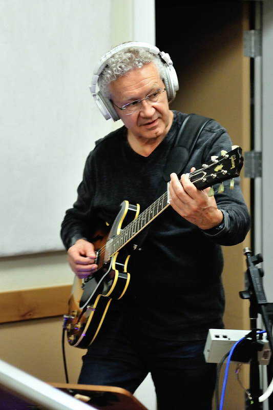 Aart de Geus wearing headphones and playing an electric guitar