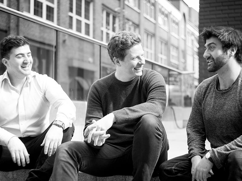 Beamery co-founders Sultan Saidov, Michael Paterson and Abakar Saidov laughing together outside an office