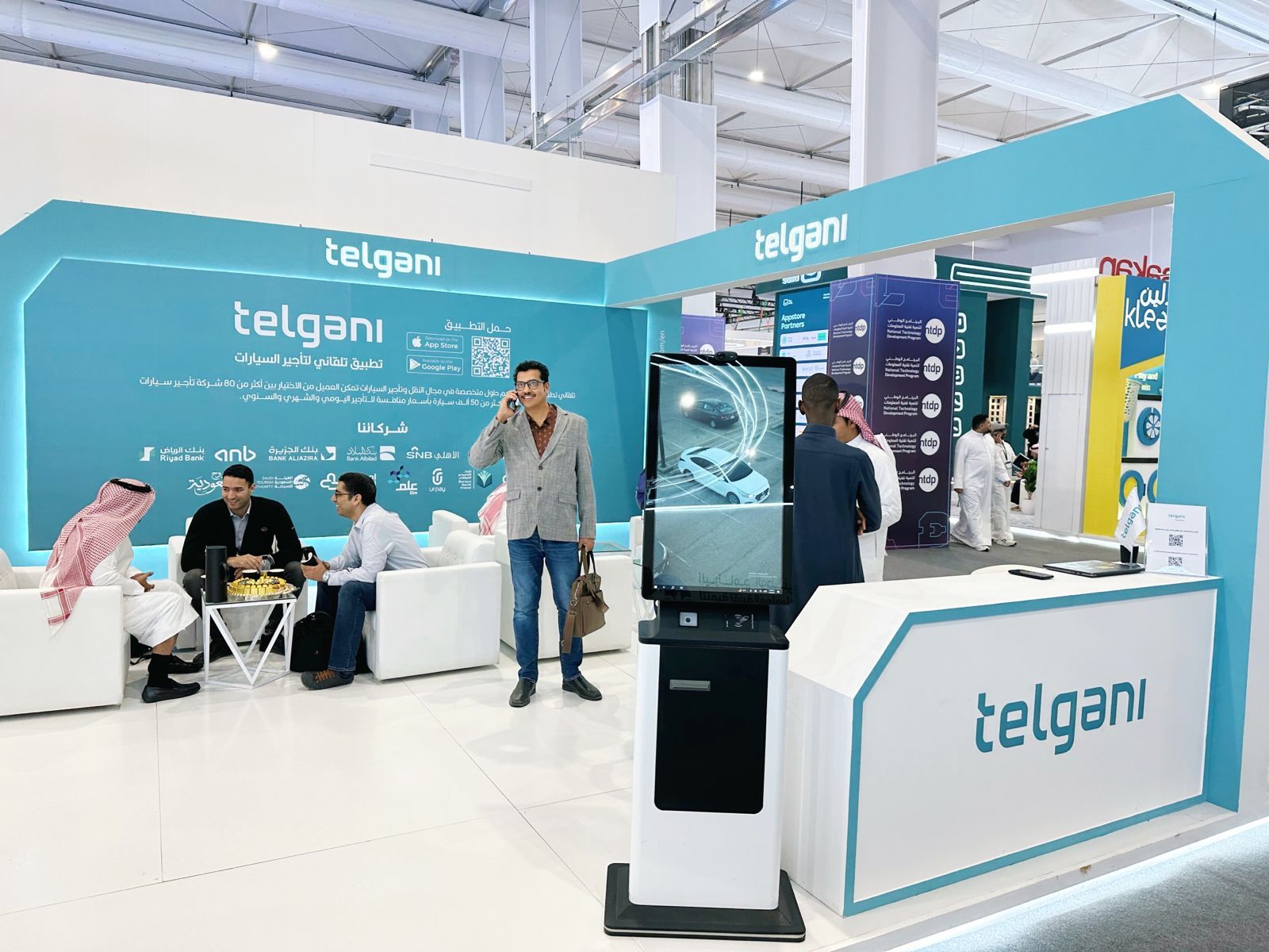 Telgani exhibition booth with staff, screens and a teal branded stand