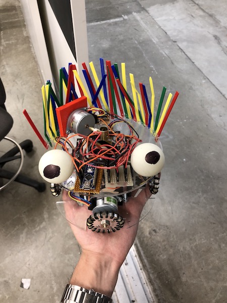 Jamjoom's jamBot drawing robot, with exposed circuitry, colored sticks and round eyes