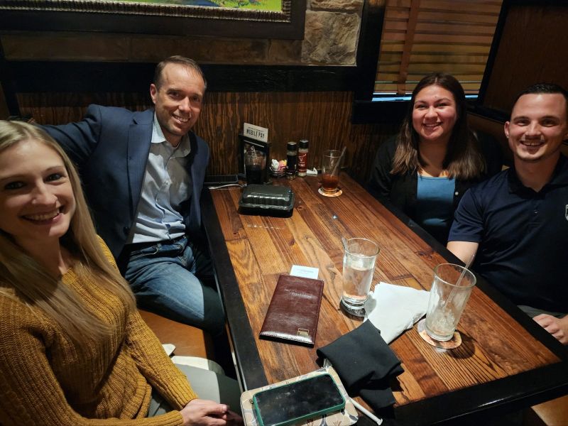 Abe Andrzejewski seated with three AMP colleagues during a 2022 team visit