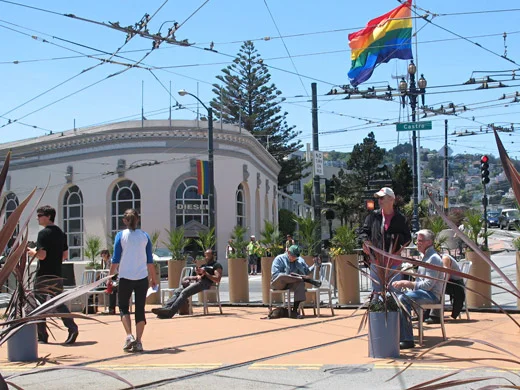 People sitting and walking among chairs and planters at Jane Warner Plaza in San Francisco