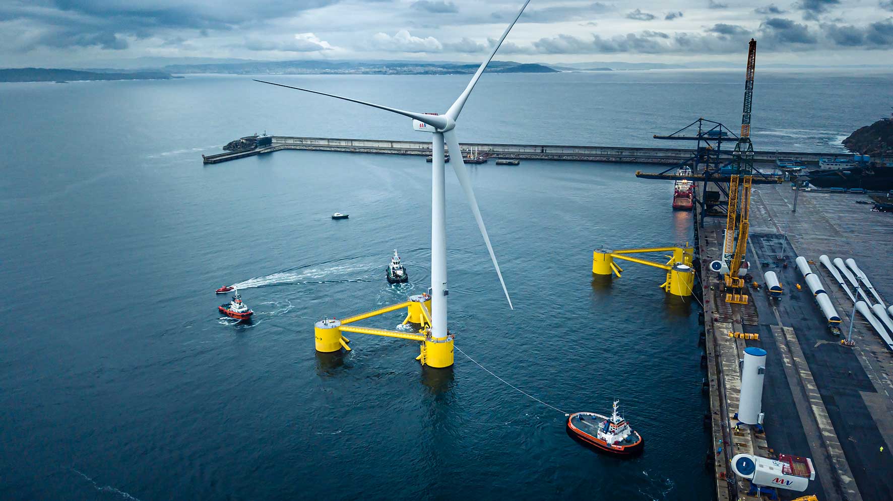 Tugs manoeuvring a floating wind turbine beside a port