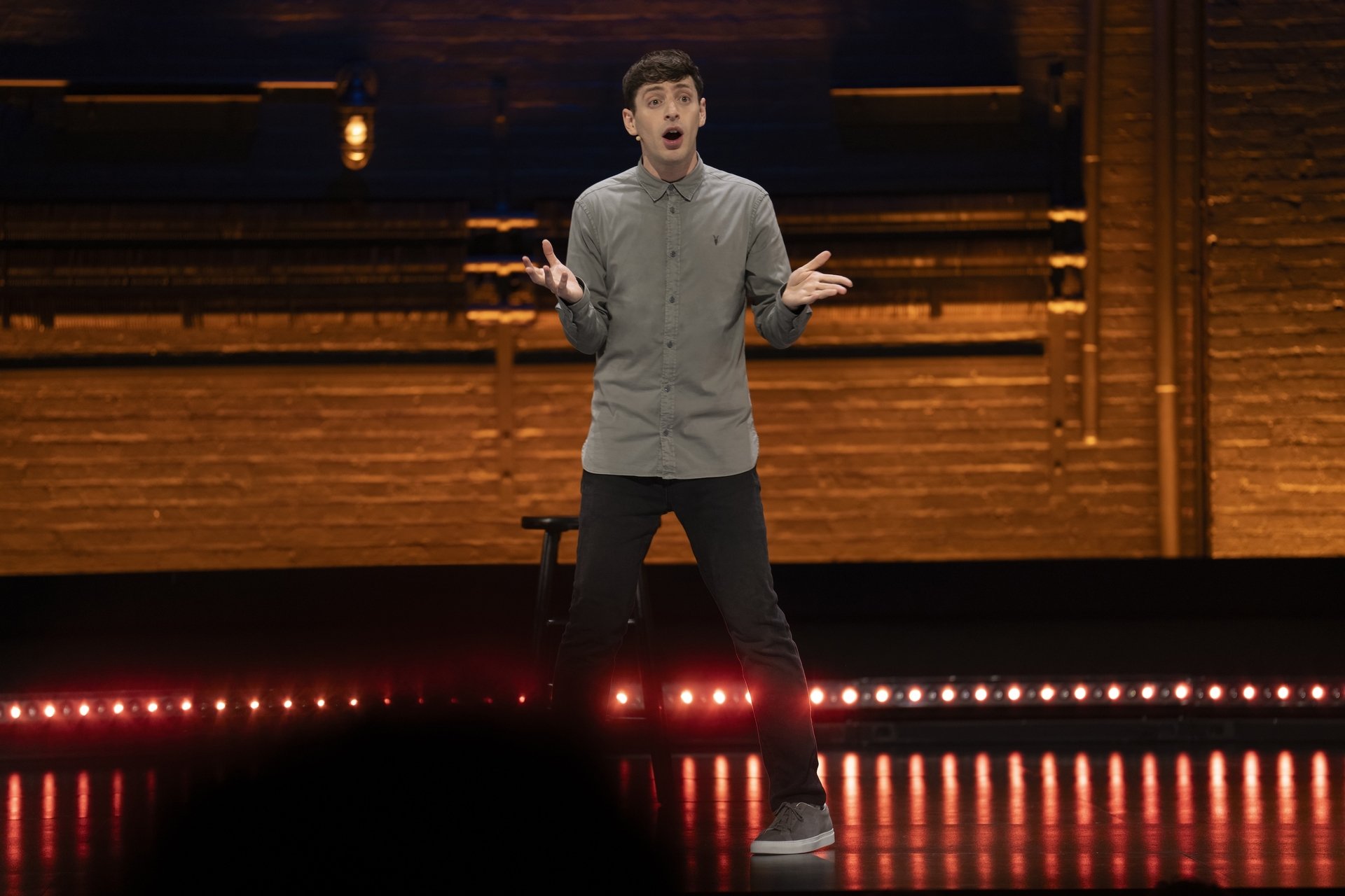 Alex Edelman on a warmly lit theater stage during Just For Us