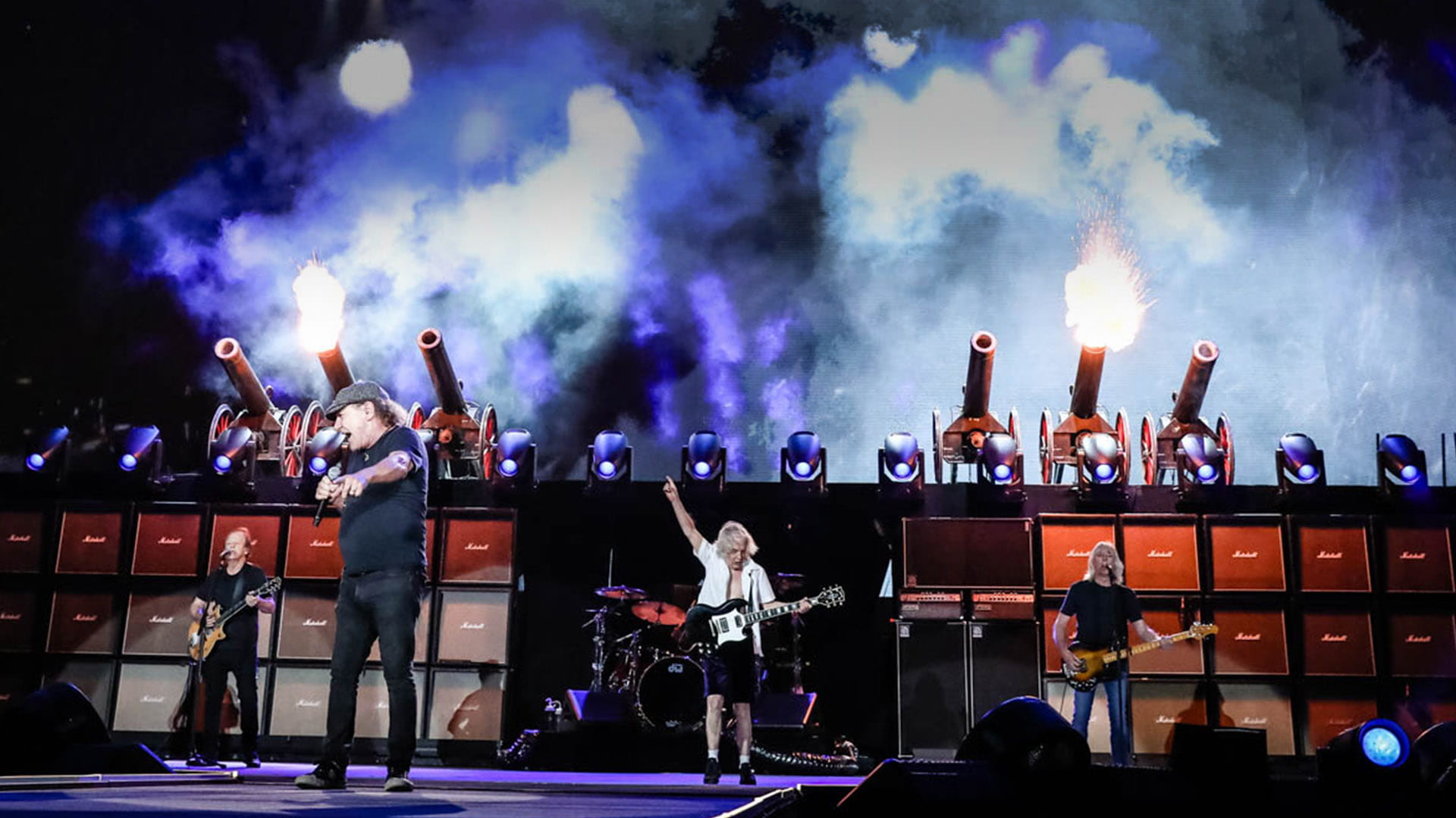 AC/DC performing at Power Trip in 2023, with Brian Johnson and Angus Young in front of amplifier stacks and firing cannons