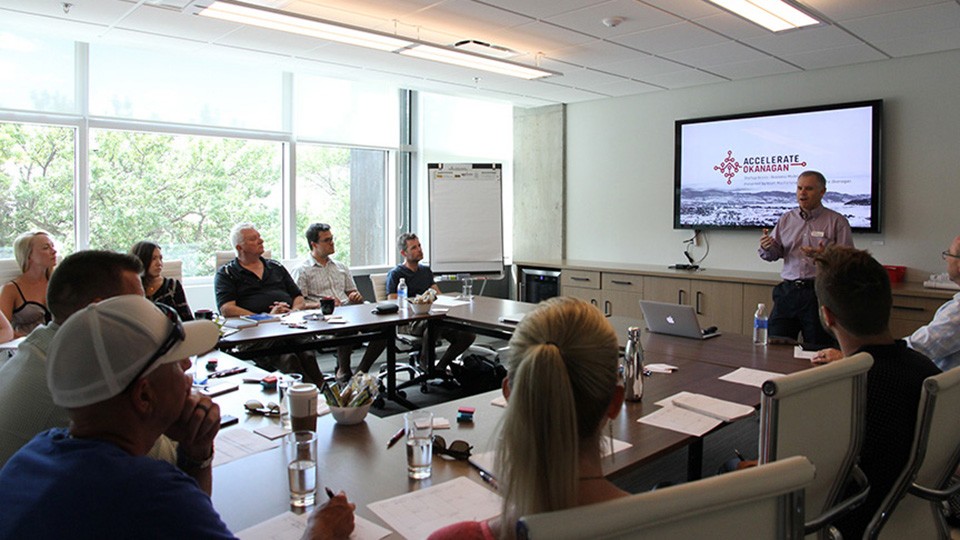 Participants seated around a boardroom table during an Accelerate Okanagan presentation