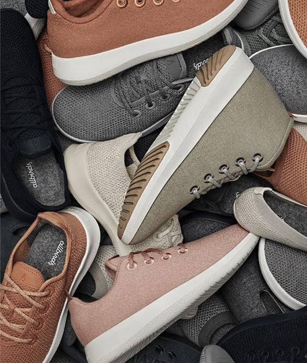 A close arrangement of Allbirds shoes in gray, olive, pink and brown
