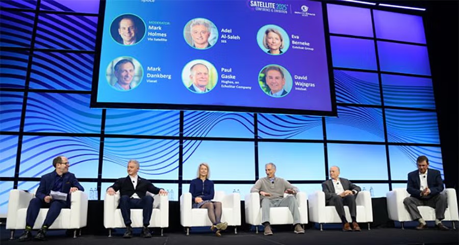 Six speakers seated beneath a screen at the SATELLITE 2025 conference
