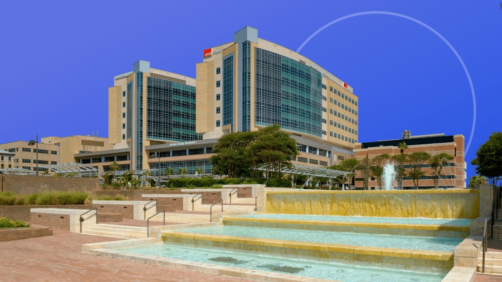 UTMB hospital campus buildings behind a landscaped fountain