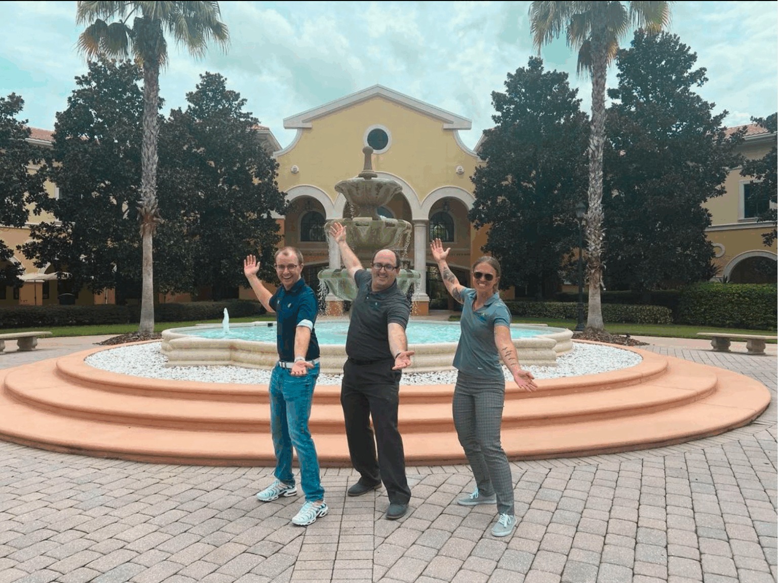 Three accesso employees standing beside a fountain at Rosen College
