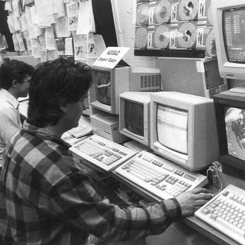 AccuWeather forecasters working at banks of monitors in an archival black-and-white operations photograph