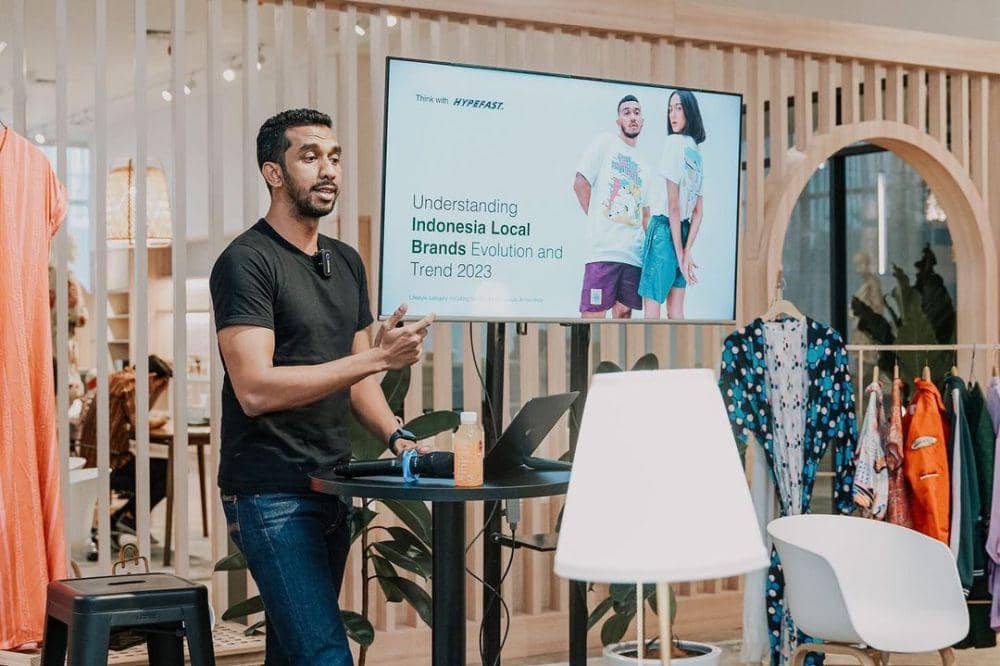 Achmad Alkatiri presenting a briefing on Indonesian local brands beside a display of clothing