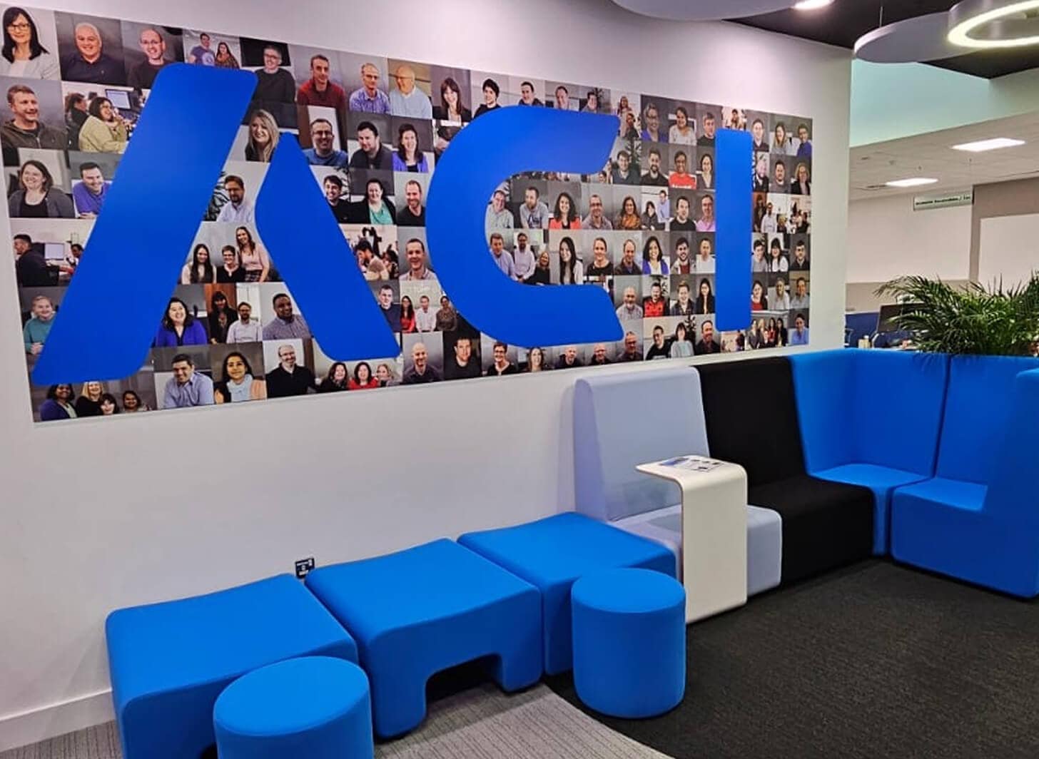 ACI office lobby with a wall of employee portraits and blue seating