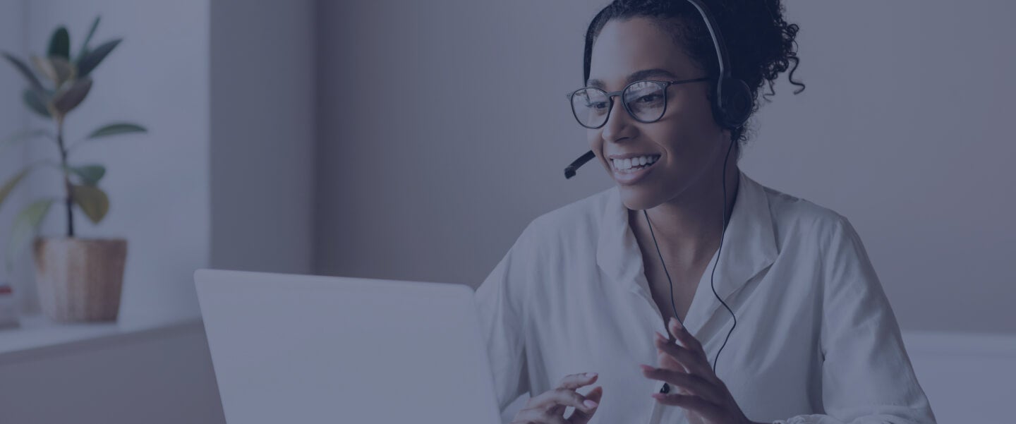 A headset-wearing agent working at a laptop in Five9’s Acqueon promotional photograph