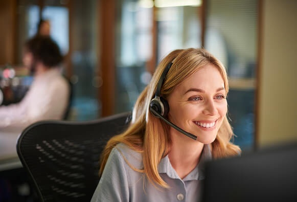 A headset-wearing contact-center agent at a computer in Five9’s Acqueon promotional photograph