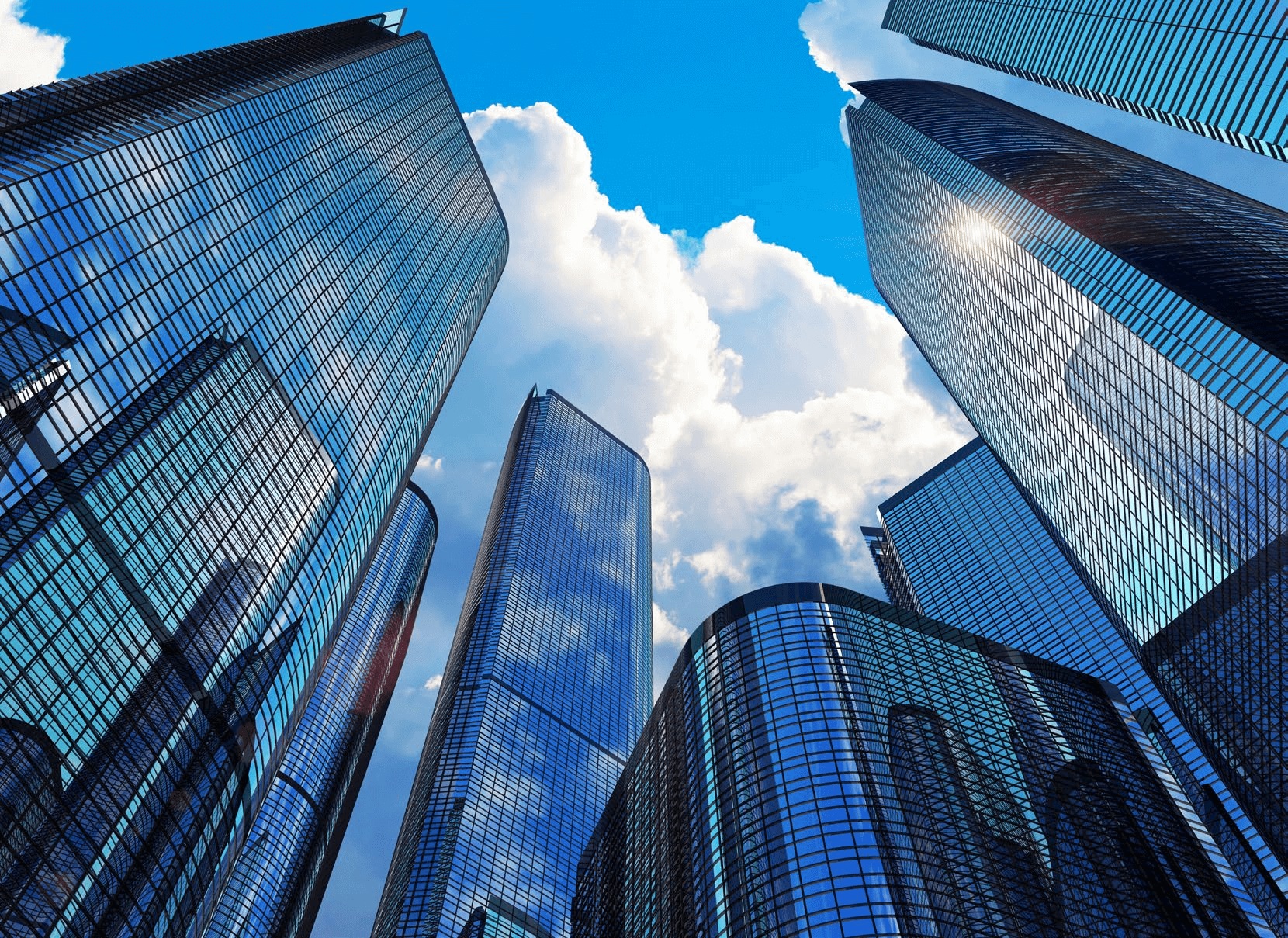 Glass commercial towers viewed from below against a blue sky
