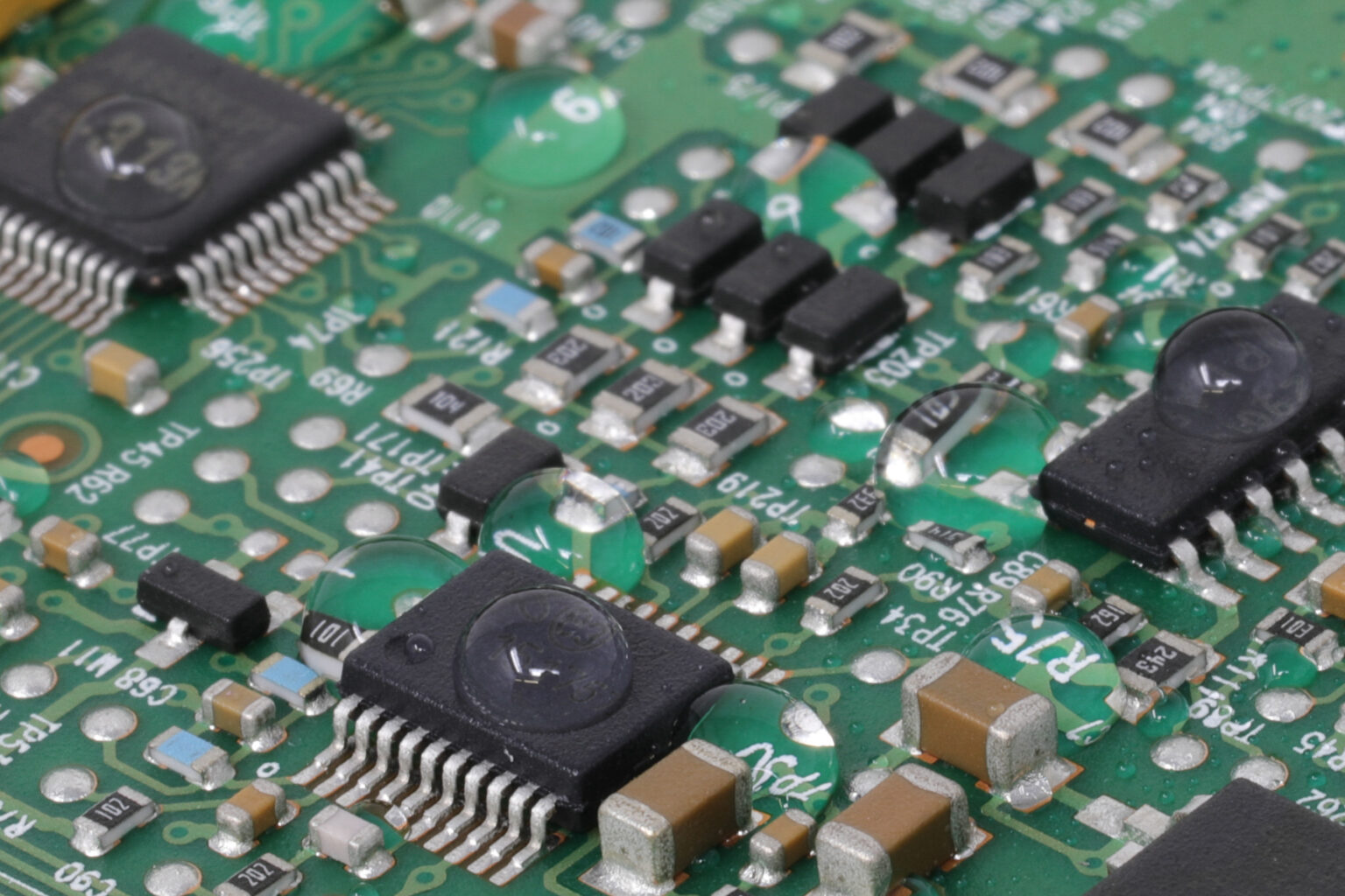 Green printed circuit board with water droplets beading on the coated surface