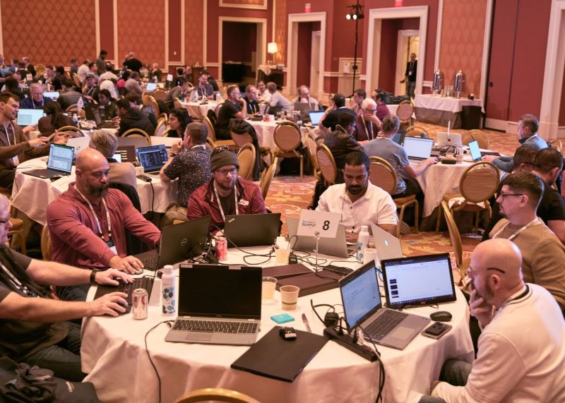 Participants collaborating around laptops at an Acumatica Summit hackathon