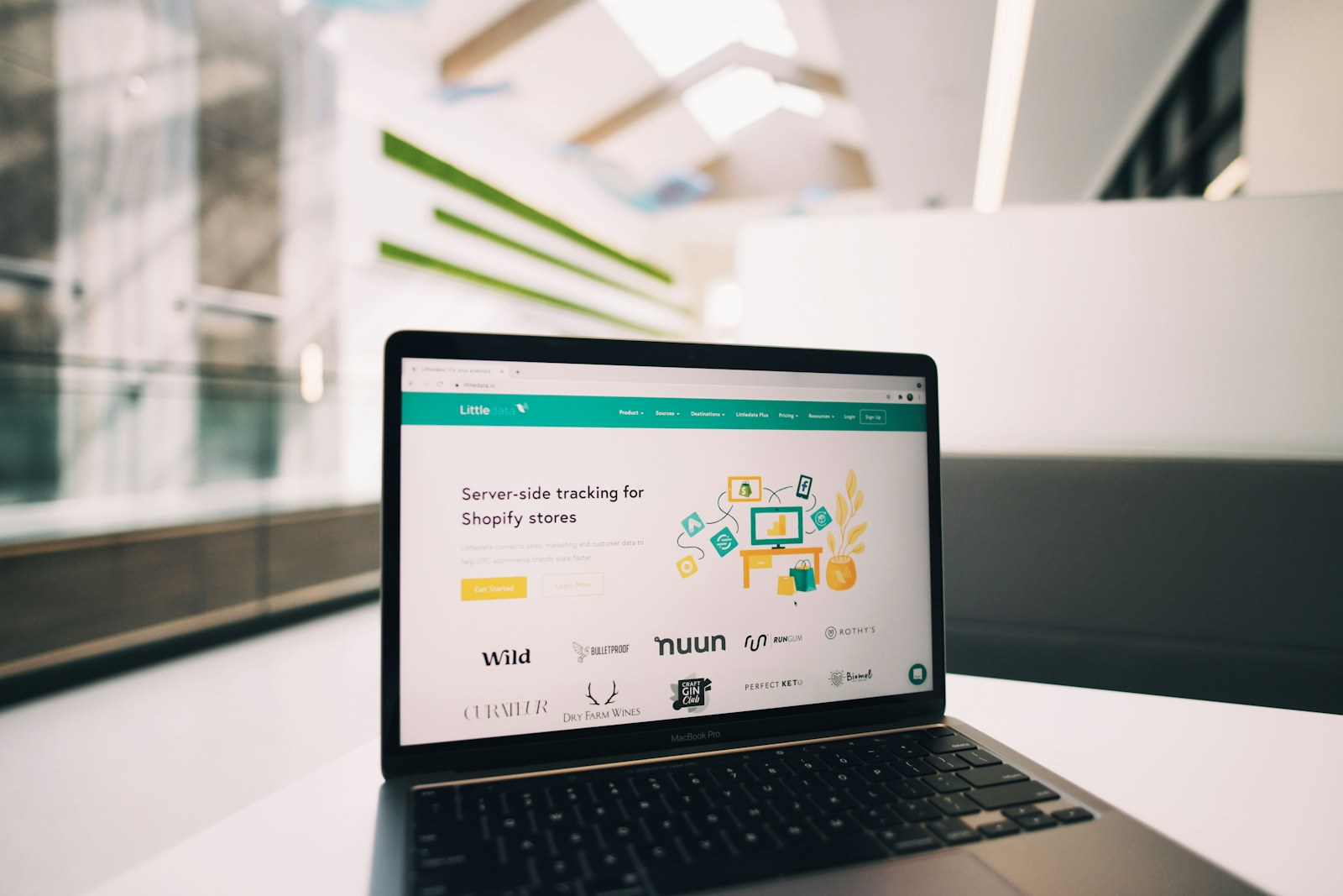 Laptop displaying a landing page on a desk in a bright workspace