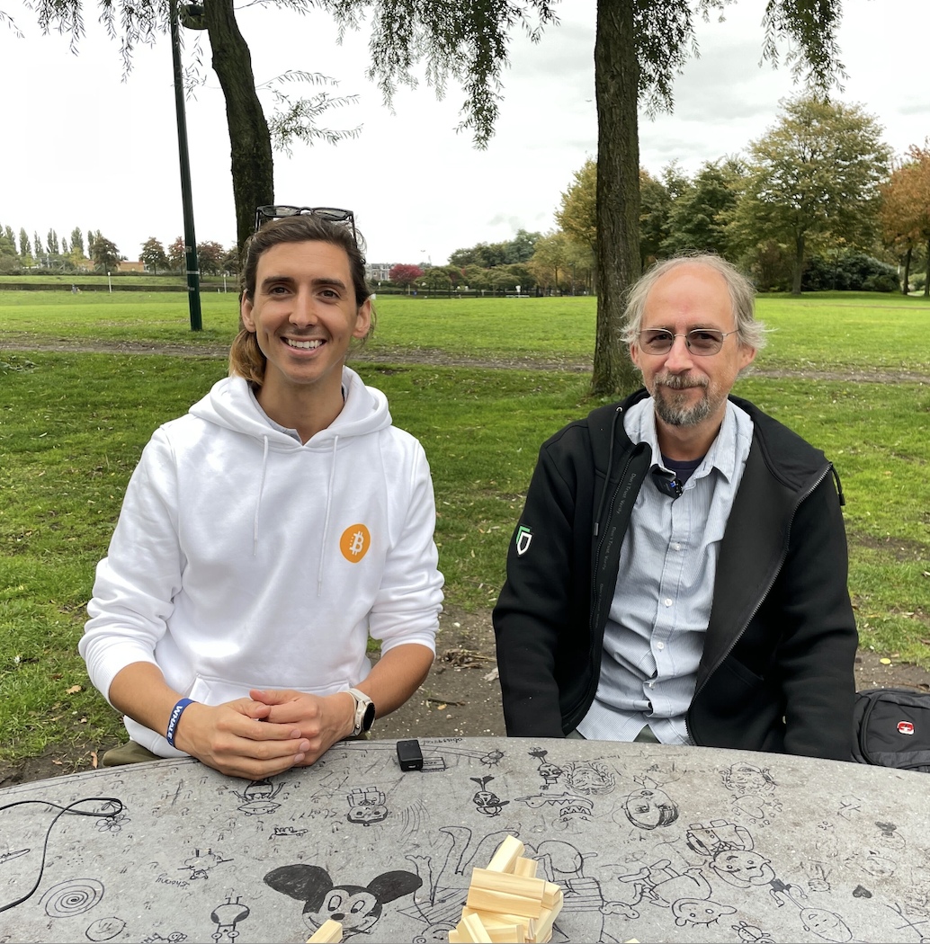Joe Hall and Adam Back sitting at a park table in Amsterdam, with Jenga blocks in the foreground.