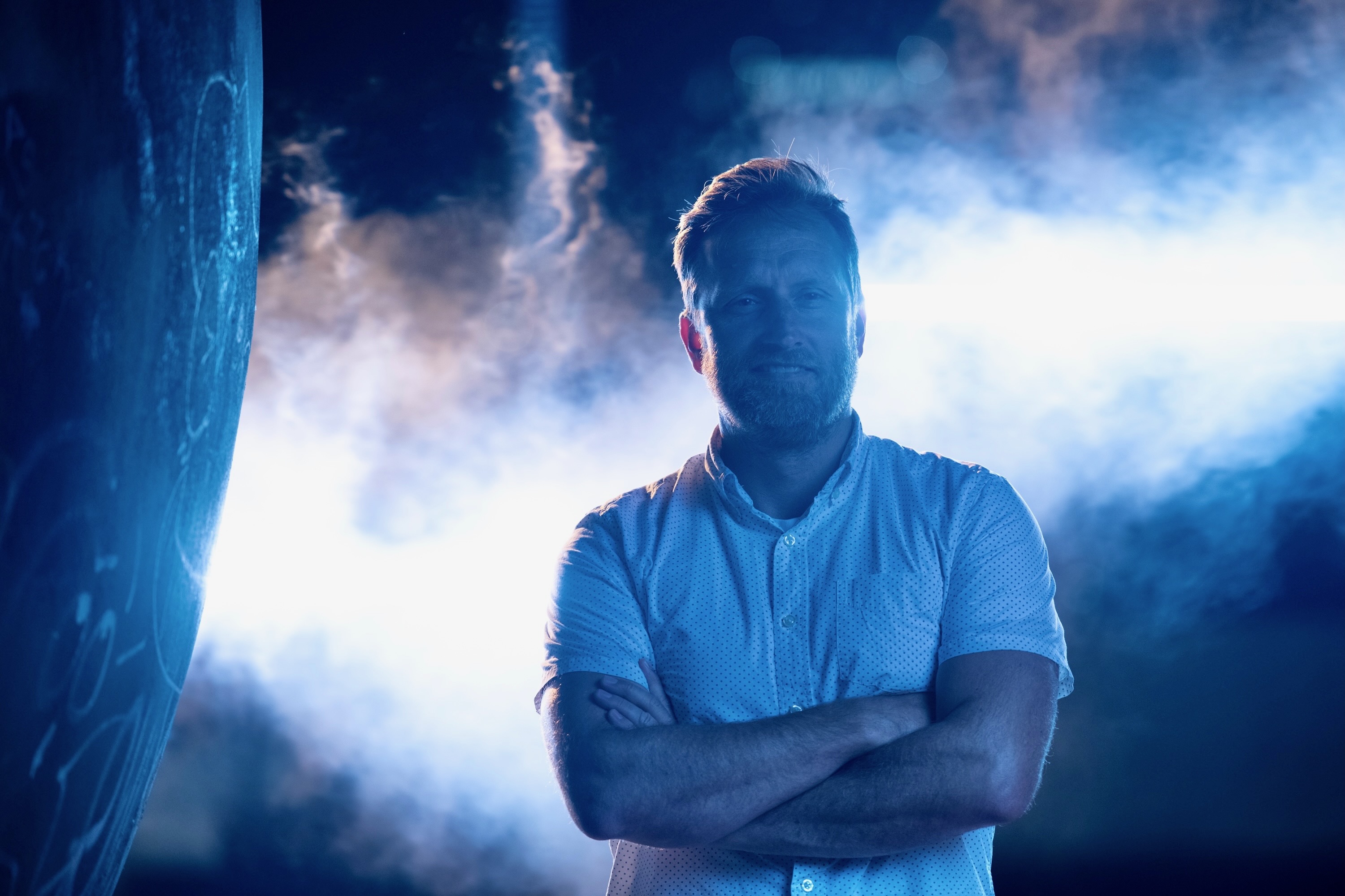 Adam Christensen standing in blue light and stage haze