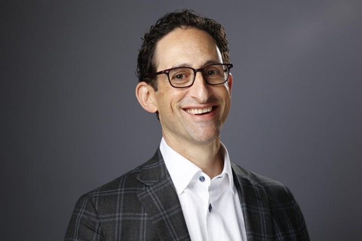 Adam Holt smiling in glasses and a checked jacket