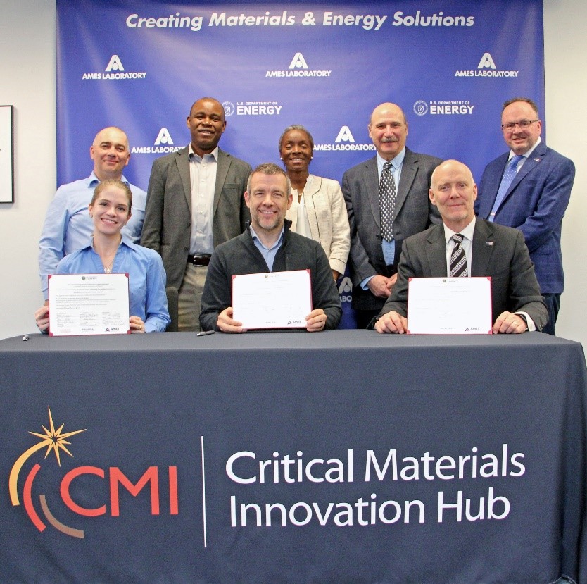 Adam Johnson seated at the center of a group at the REMAFS technology license signing at Ames National Laboratory.