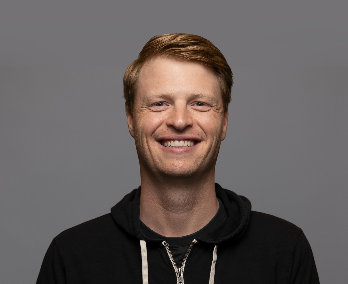 Adam Pettit smiling in a black hoodie